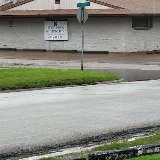 A view of a flooded street with a nearby building and a street sign.