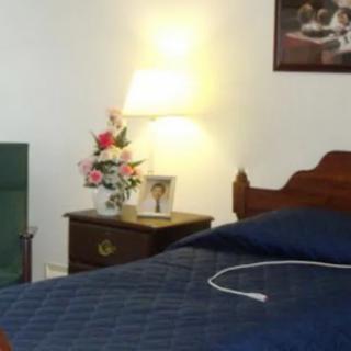A cozy bedroom with a lamp and floral arrangement on the nightstand.