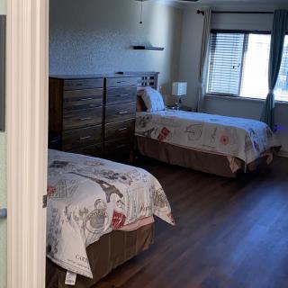 A cozy bedroom with two single beds, wooden furniture, and a window letting in natural light.