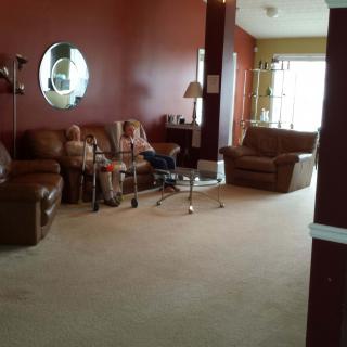 A cozy living room with red walls, furnished with a sofa, armchairs, and a glass coffee table.