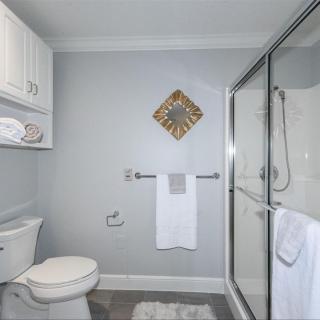 A modern bathroom featuring a toilet, shower, and neatly arranged towels.