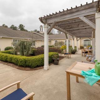 A serene outdoor patio with a pergola, surrounded by lush garden landscaping.