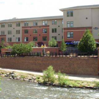 A riverside apartment building with trees lining the waterfront.