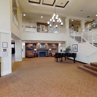 A spacious and elegant lobby featuring a grand piano, chandelier, and staircase.