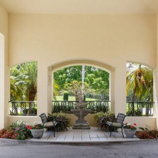 Elegant outdoor patio area with a central fountain, surrounded by lush greenery and seating.