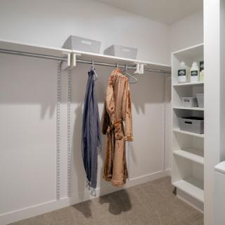 A well-organized closet featuring hanging clothes and neatly arranged shelving.