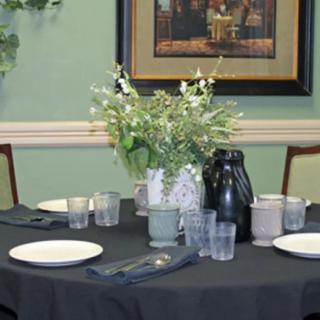 A neatly set dining table with a floral centerpiece, surrounded by plates, glasses, and napkins.