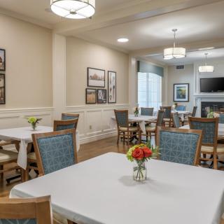 A well-lit dining room with neatly arranged tables and chairs, featuring tasteful decor and floral centerpieces.