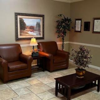 A cozy and well-decorated waiting room with leather chairs, a coffee table, and artwork on the wall.