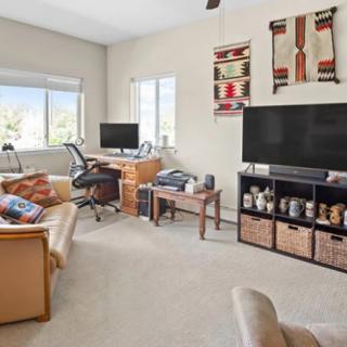 A cozy living room with a home office setup, featuring a TV, computer desk, and comfortable seating.
