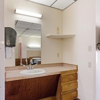 A simple and functional bathroom setup featuring a sink, mirror, and wooden cabinetry.