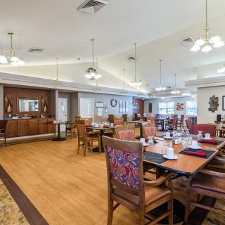 A spacious and elegantly decorated dining room with wooden floors, tables, and chairs.