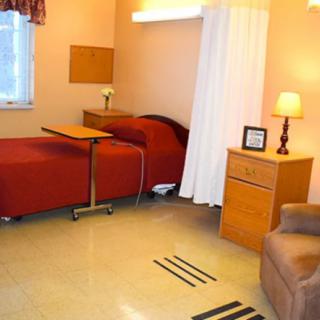 A neatly arranged hospital room with a single bed, side table, and curtain divider.