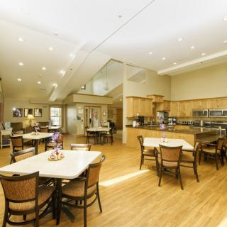 A spacious and well-lit dining area with a modern kitchen setup, featuring wooden floors and stylish furniture.