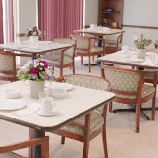 A serene and elegantly arranged dining area, featuring neatly set tables and decorative flowers.