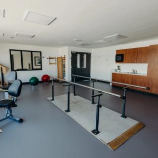 A rehabilitation room equipped with parallel bars and exercise tools.