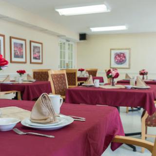 A beautifully arranged dining area featuring red tablecloths and floral centerpieces, ready for guests.