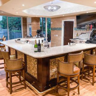 A stylish bar interior with seating around a marble counter and ambient lighting.