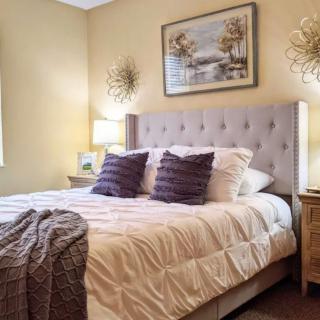 A cozy and well-decorated bedroom with a tufted headboard, plush pillows, and soft lighting.