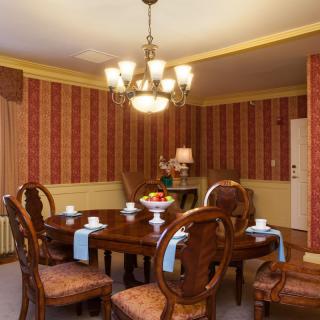 A traditional dining room with a wooden table and chairs, featuring a chandelier and warm decor.