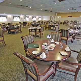 An empty, formal dining room with neatly arranged tables and chairs.