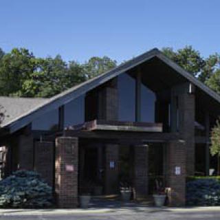 A modern building with large windows, surrounded by trees under a clear blue sky.