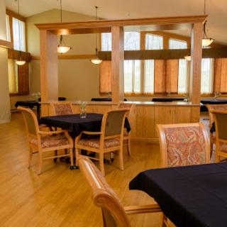 A spacious dining area featuring wooden furniture and large windows that allow natural light to fill the room.