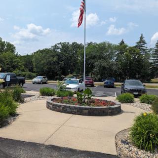 A peaceful outdoor area featuring an American flag and a landscaped circular garden in a parking lot.