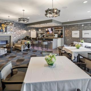 A modern restaurant interior with dining tables and elegant chandeliers.