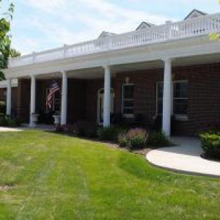 A brick building with white columns and a well-maintained lawn.