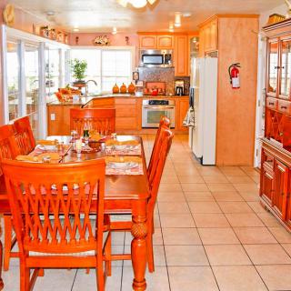A bright kitchen and dining area featuring orange-toned wooden furniture and tile flooring.