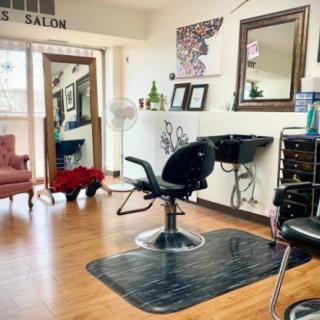 A cozy salon interior with a styling chair, mirror, and elegant decor.