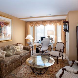 A cozy living room with an integrated office space featuring a sofa, chairs, coffee table, and desk by the window.