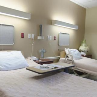 An empty hospital room with two beds and medical equipment.
