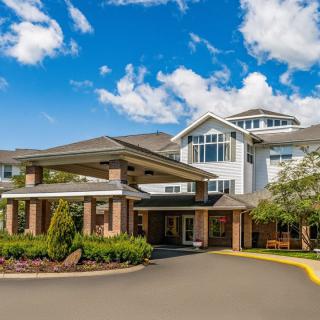 A multi-story residential building with a landscaped entrance under a bright blue sky.