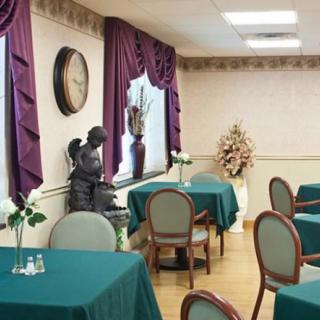 A dining room with teal tablecloths, draped windows, and a decorative statue.