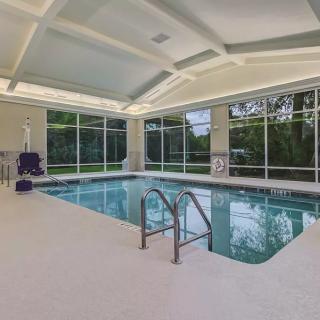 A modern indoor swimming pool with large windows allowing natural light.
