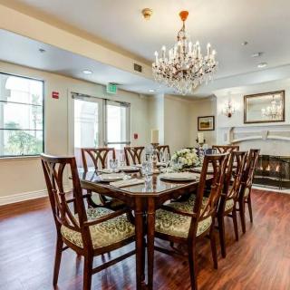 Elegant dining room with a chandelier, a large table, and chairs on a wooden floor.