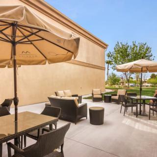 A sunny outdoor patio with tables, chairs, and umbrellas.
