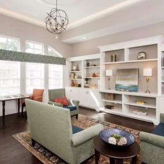 A modern living room featuring comfortable seating, built-in shelves, and stylish decor.