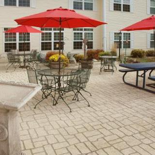 Outdoor patio with tables, chairs, and red umbrellas.