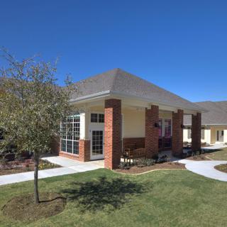 A modern brick house with a well-maintained lawn and clear blue sky.