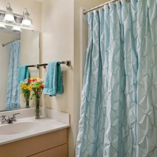 A cozy bathroom with a light blue shower curtain and matching towels.