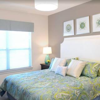 A cozy bedroom with patterned bedding and decorative artwork above the bed.
