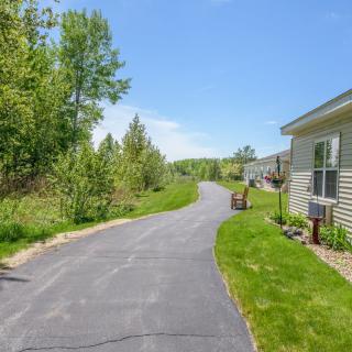 A sunny suburban driveway with green grass and trees lining the path.