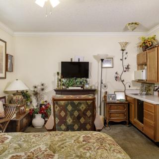 A cozy bedroom with a television, floral bedspread, and assorted decor.