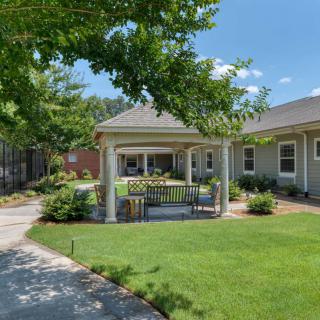 A beautifully landscaped garden featuring a gazebo and pathway leading through lush greenery.