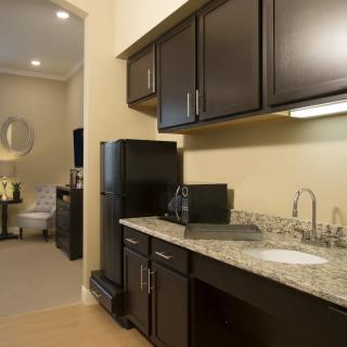 A modern apartment kitchen with dark cabinets and granite countertops.