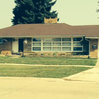A suburban single-story house with a well-maintained lawn and driveway.