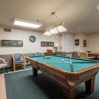 A cozy billiard room with a pool table and comfortable seating.